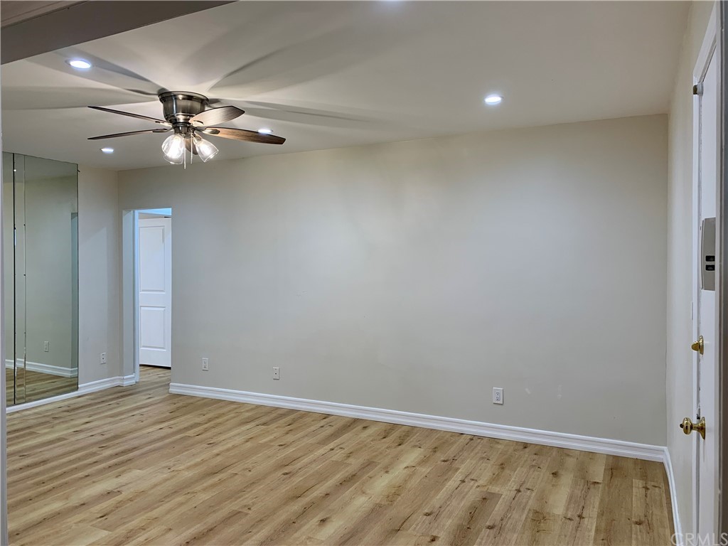 an empty room with wooden floor closet and fan