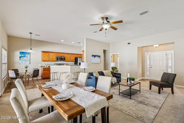a living room with furniture kitchen view and a wooden floor