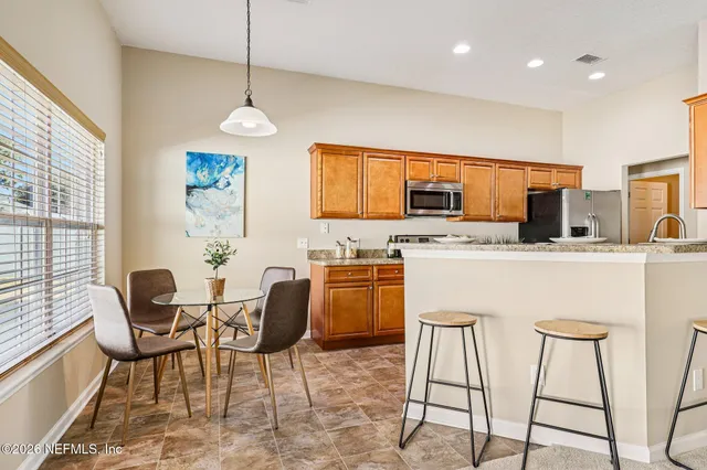 a kitchen with stainless steel appliances granite countertop a stove a sink a microwave a dining table and chairs with wooden floor