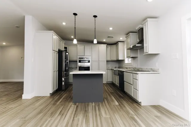 a kitchen with kitchen island a counter top space a sink stainless steel appliances and cabinets