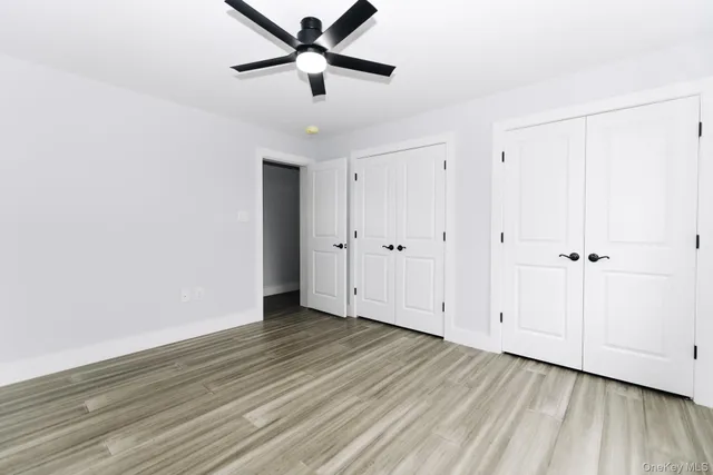 an empty room with wooden floor closet and ceiling fan
