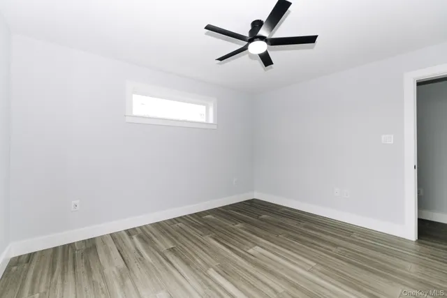an empty room with wooden floor and a ceiling fan