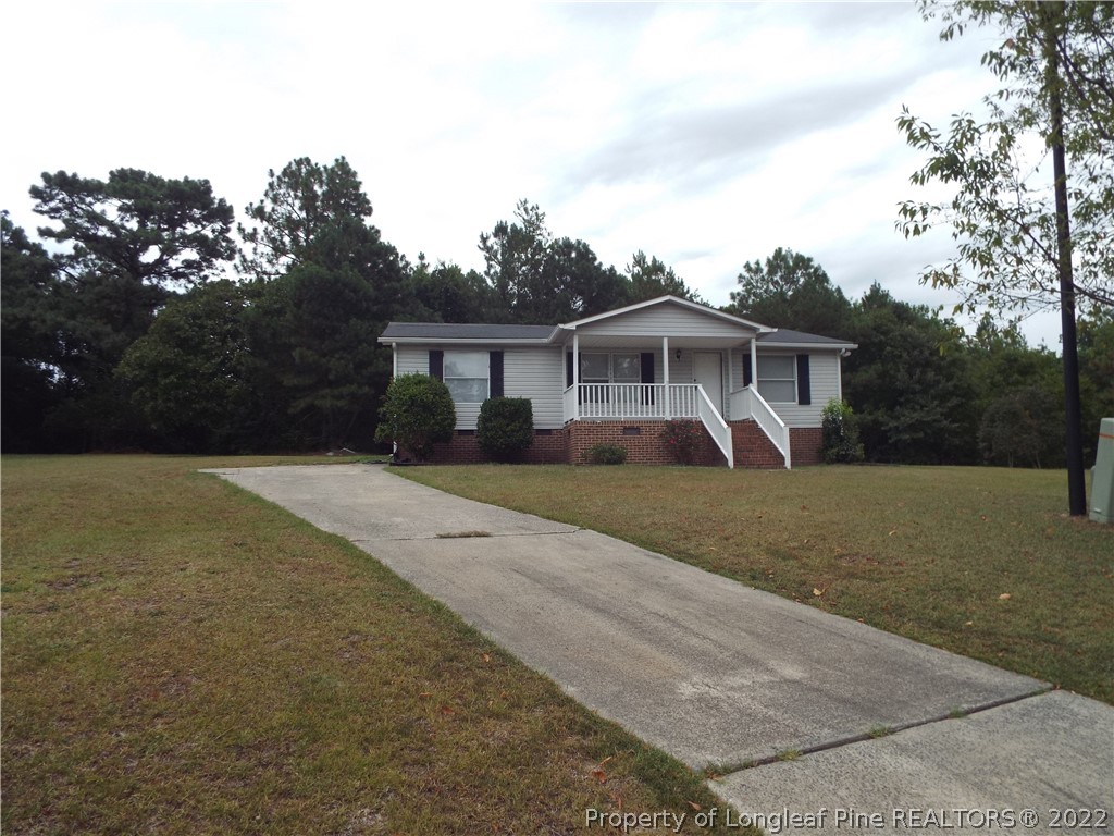 a front view of house with yard and trees in the background