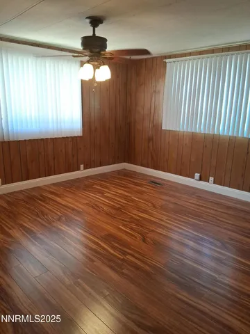 an empty room with wooden floor fan and windows