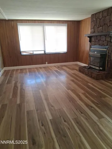 an empty room with wooden floor fireplace and windows