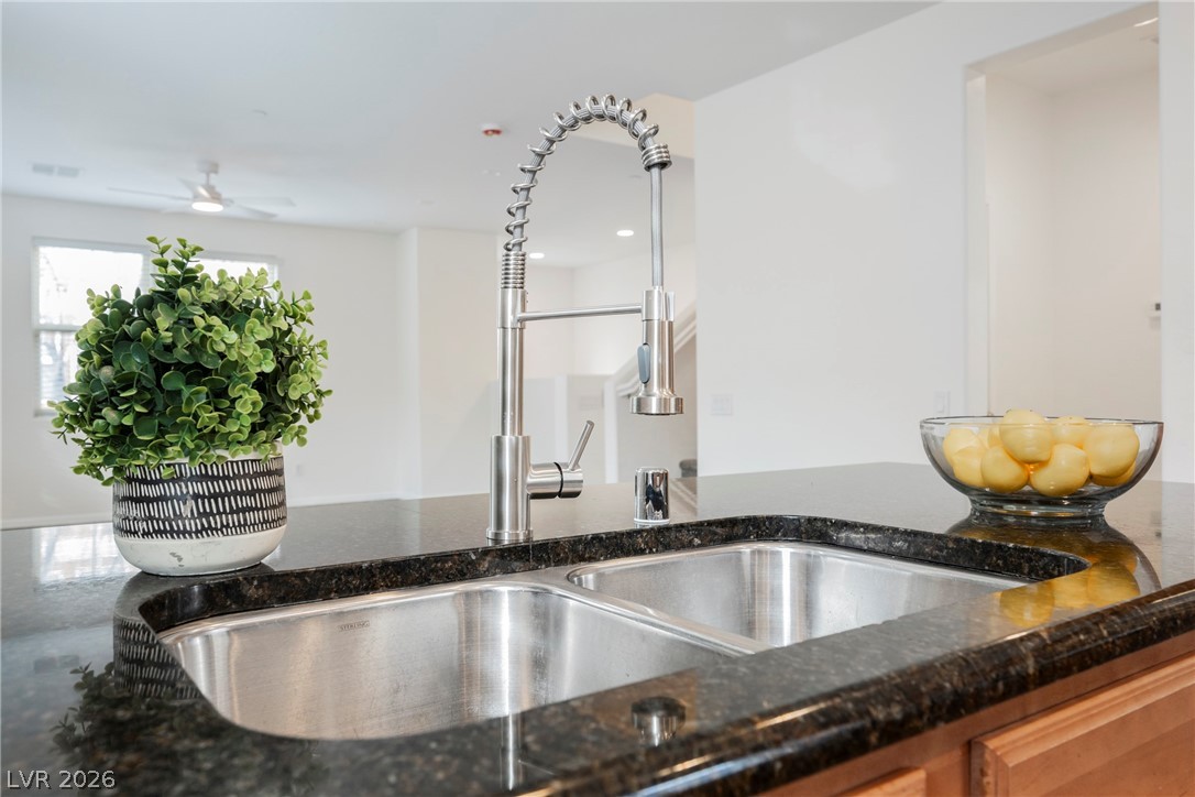4650 Ranch House Road, Unit 64 North Las Vegas, NV 89031 - Photo 20 of 39 This modern kitchen features dark granite countertops, a double basin sink with a high-arc pull-down faucet, and light wood cabinetry.