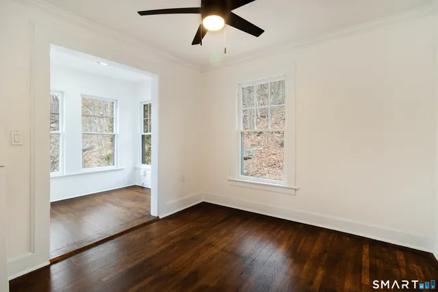 a view of an empty room with wooden floor and a window