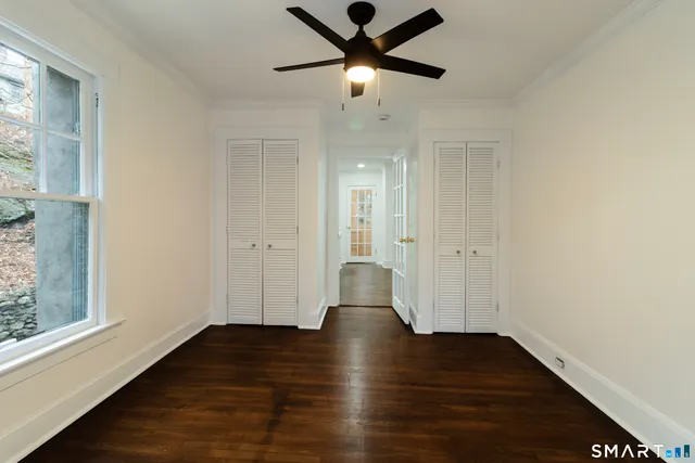 a view of empty room with wooden floor and fan