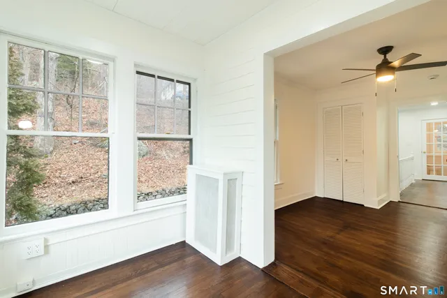 a view of an empty room with wooden floor and a window