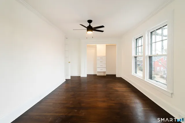 an empty room with wooden floor fan and windows
