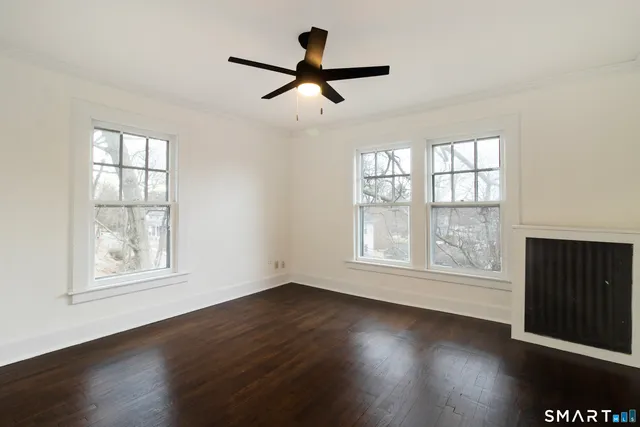 a view of empty room with wooden floor and fan