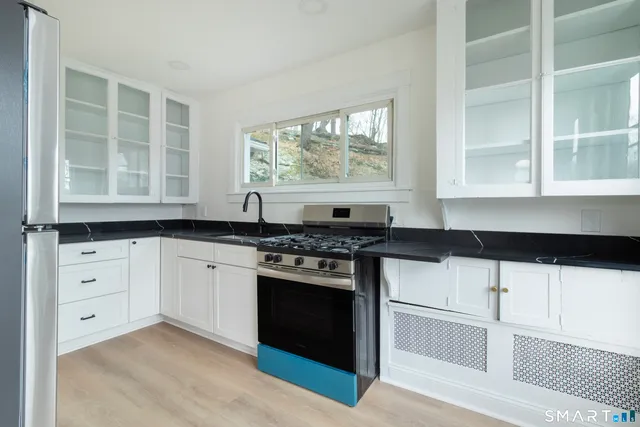 a kitchen with stainless steel appliances a stove a sink and white cabinets