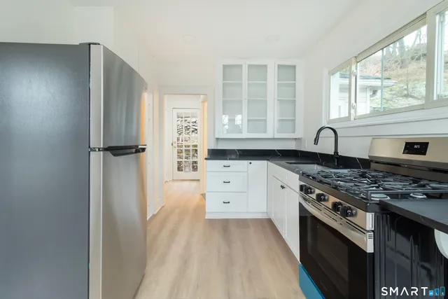 a kitchen with granite countertop a sink stove and refrigerator