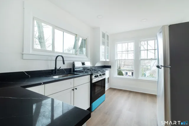a kitchen with granite countertop a stove a sink and a window