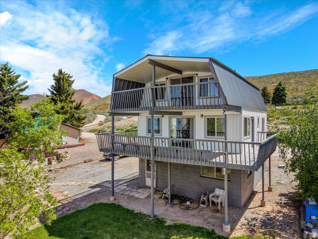 85 B Street, Unit 22 St. Charles, ID 83272 - Photo 2 of 35 White-sided gambrel-roof structure featuring a covered upper-level balcony, an open lower-level deck, dark gray metal roofing, and multiple windows