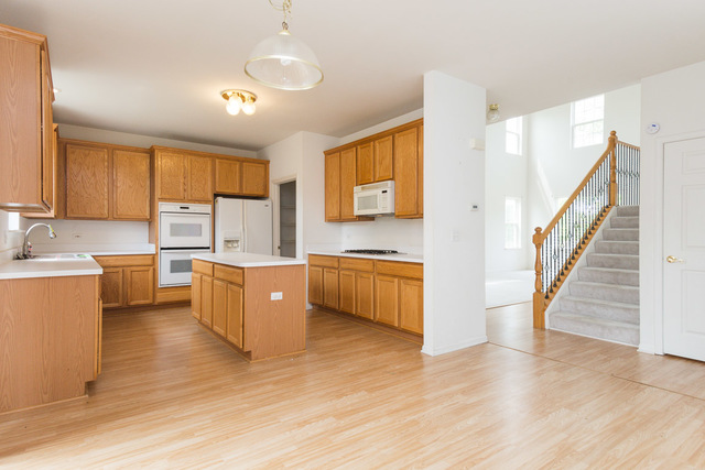 1605 Manhattan Street Bolingbrook, IL 60490 - Photo 15 of 29 a large white kitchen with wooden floors and stainless steel appliances
