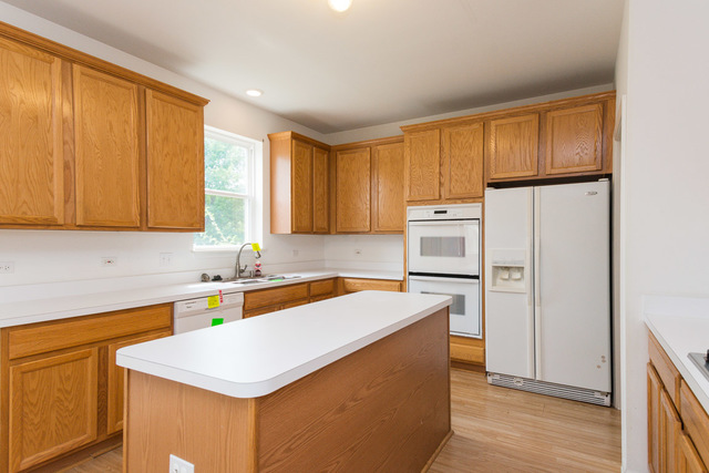 1605 Manhattan Street Bolingbrook, IL 60490 - Photo 17 of 29 a kitchen with wooden cabinets and white appliances