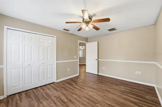 an empty room with wooden floor a ceiling fan and closet