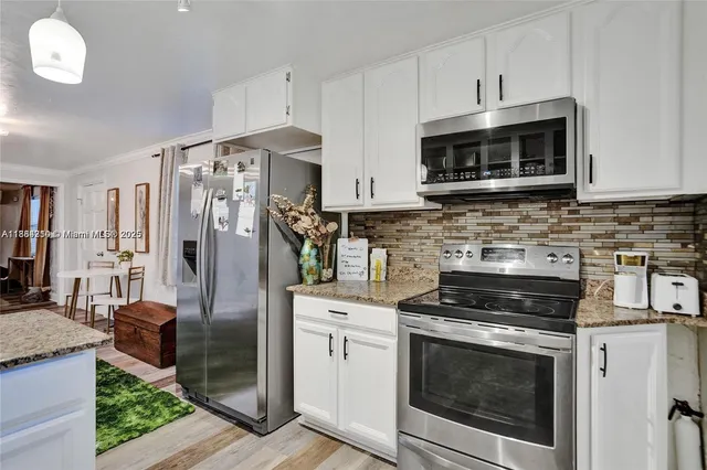 a kitchen with stainless steel appliances granite countertop a stove a microwave and a refrigerator