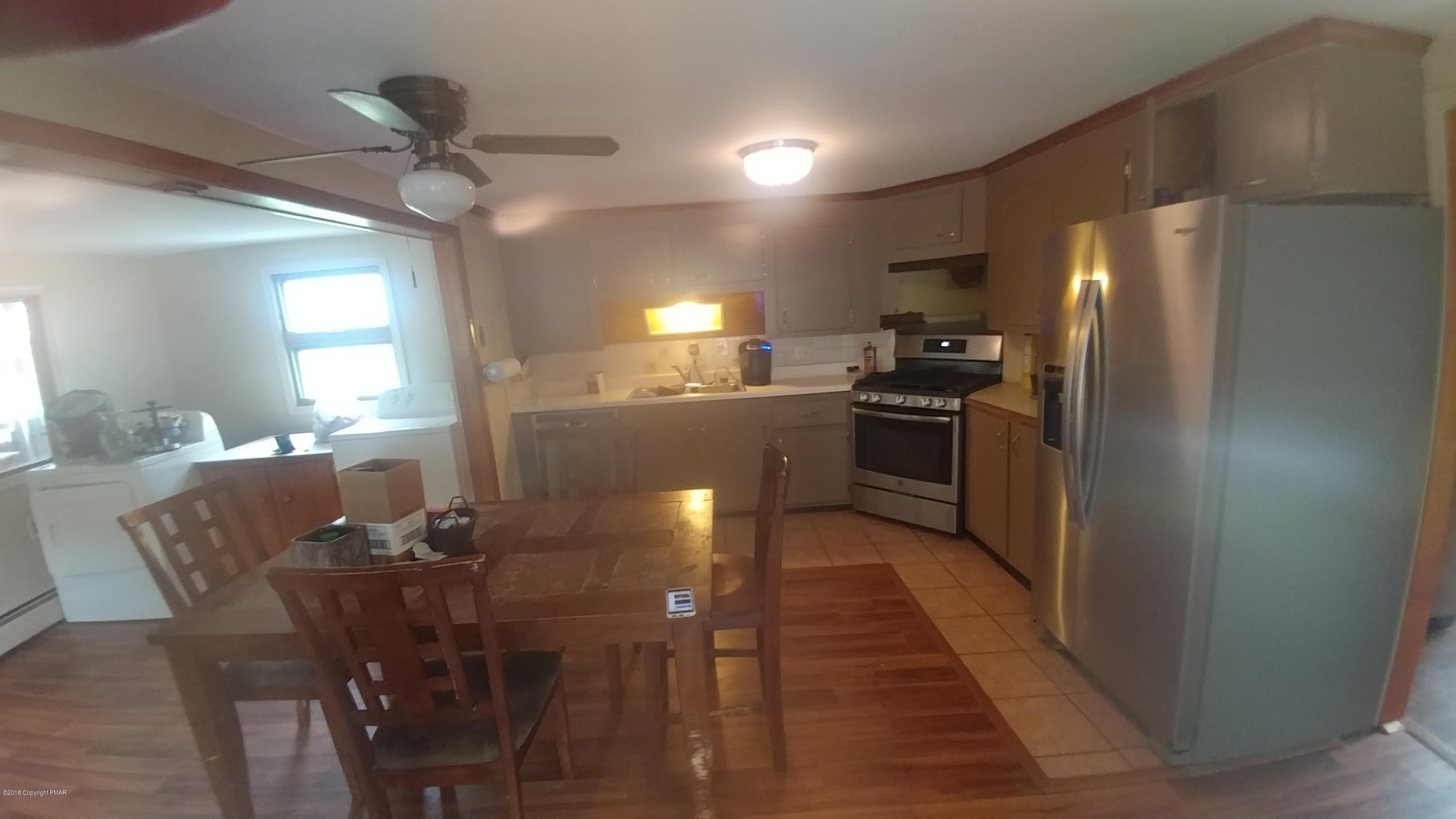 604 Lilly Lake Road Wapwallopen, PA 18660 - Photo 7 of 16 a kitchen with stainless steel appliances kitchen island granite countertop a table chairs in it and wooden floors