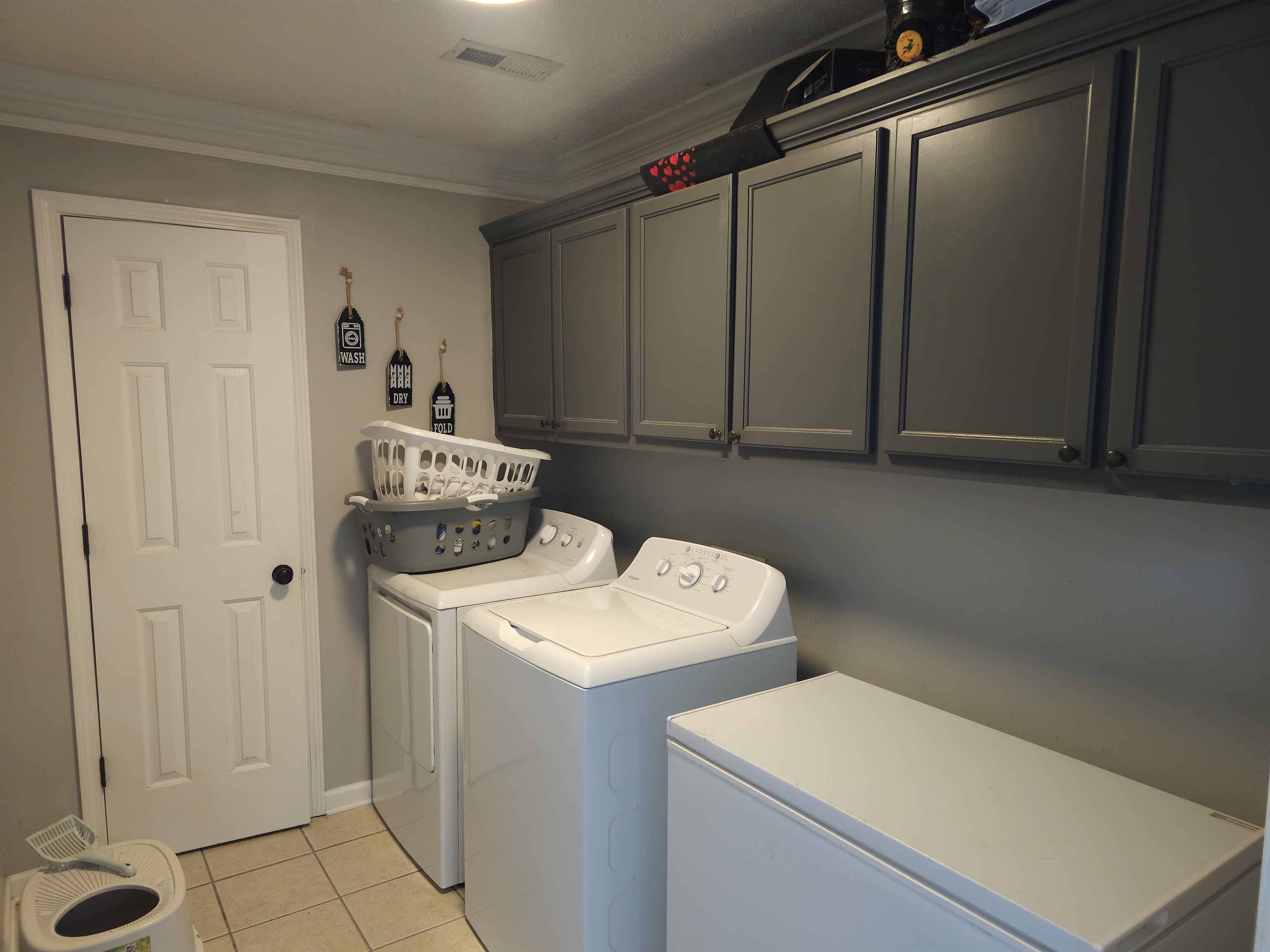 109 Sebastian Drive Jackson, TN 38305 - Photo 21 of 24 Laundry room featuring cabinet space, ornamental molding, light tile patterned floors, and separate washer and dryer