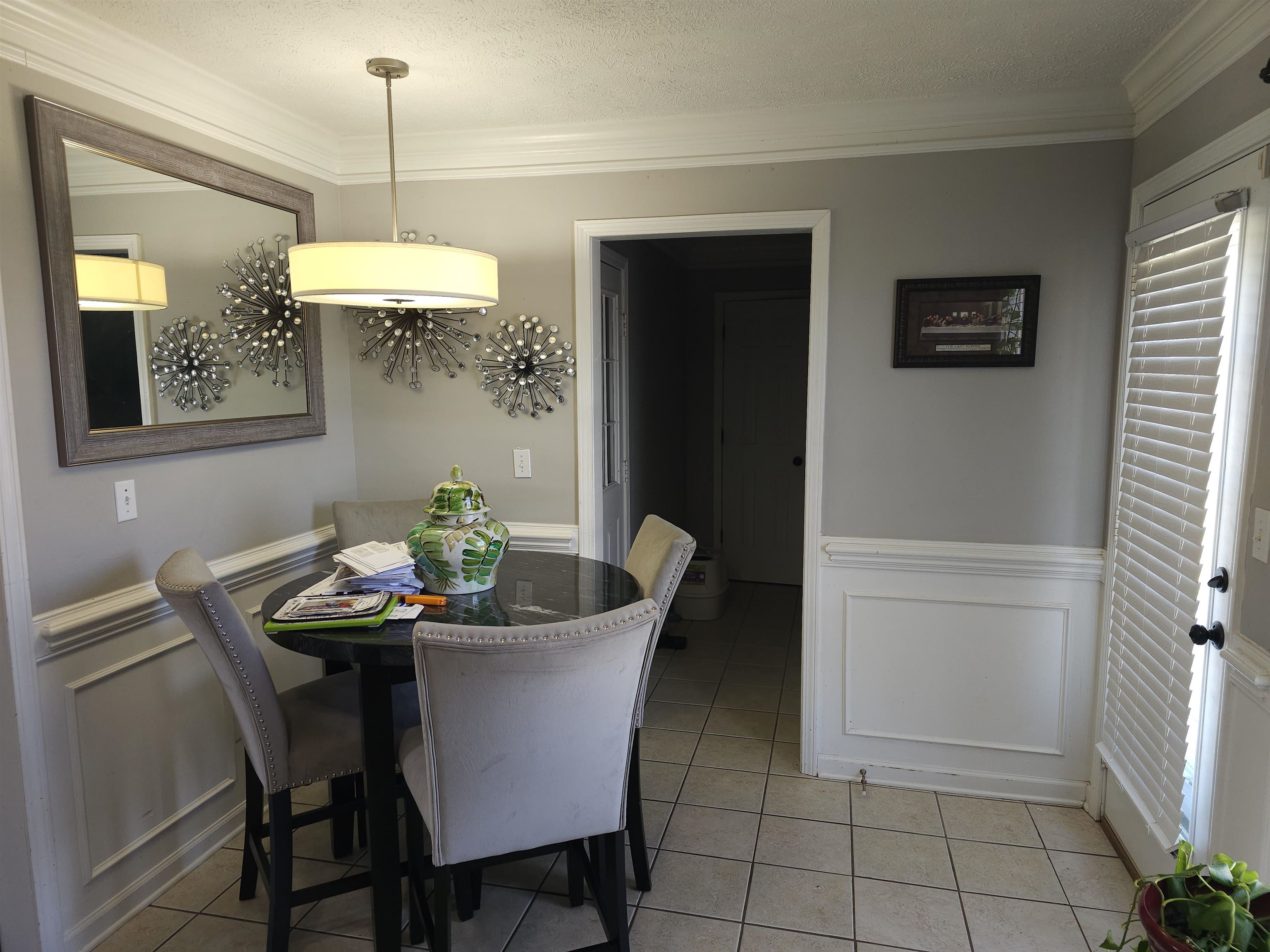 109 Sebastian Drive Jackson, TN 38305 - Photo 7 of 24 Dining area featuring a decorative wall, a wainscoted wall, crown molding, light tile patterned floors, and a textured ceiling