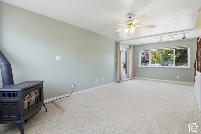 380 North 300 East Mapleton, UT 84664 - Photo 6 of 35 Expansive room with neutral carpeting, a black cast iron stove on tiled flooring, and a ceiling fan