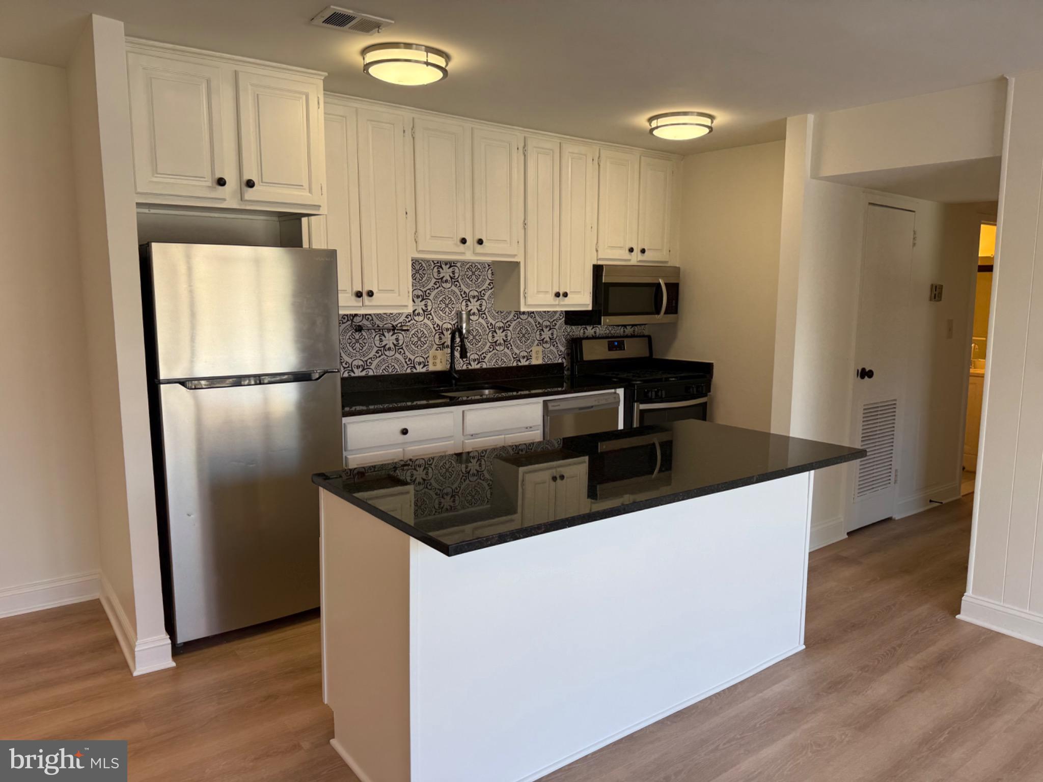3842 Bel Pre Road, Unit 12 Silver Spring, MD 20906 - Photo 4 of 14 a kitchen with kitchen island granite countertop stainless steel appliances a refrigerator a stove a microwave and cabinets