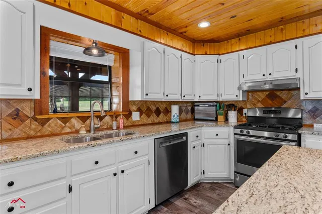 a kitchen with stainless steel appliances granite countertop a table chairs sink and cabinets