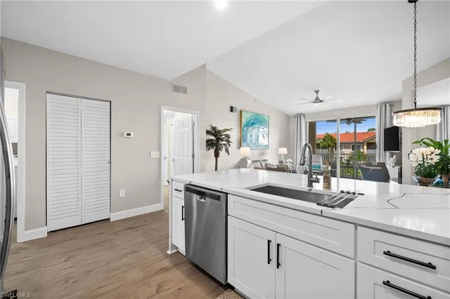 a kitchen with stainless steel appliances granite countertop a sink and a wooden floor