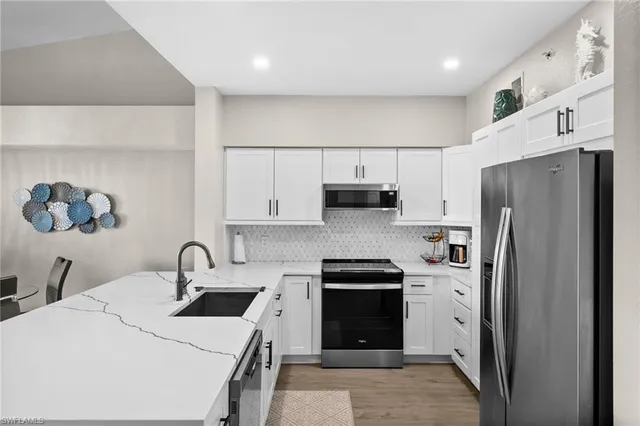 a kitchen with stainless steel appliances a refrigerator sink and white cabinets
