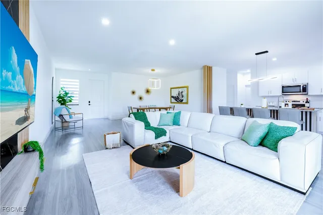 a kitchen with stainless steel appliances granite countertop a stove a sink a microwave a dining table and chairs with wooden floor