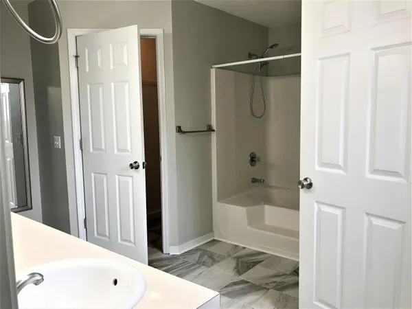 a bathroom with a bathtub shower and a sink