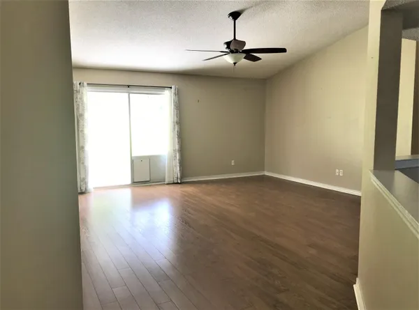 a view of an empty room with a window and wooden floor
