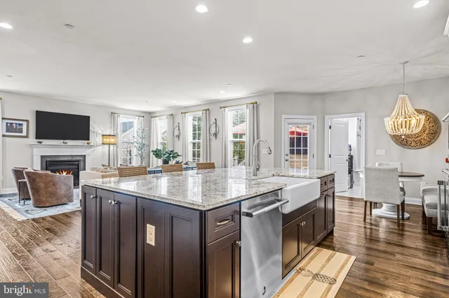 a kitchen with stainless steel appliances granite countertop a dining table chairs refrigerator and sink
