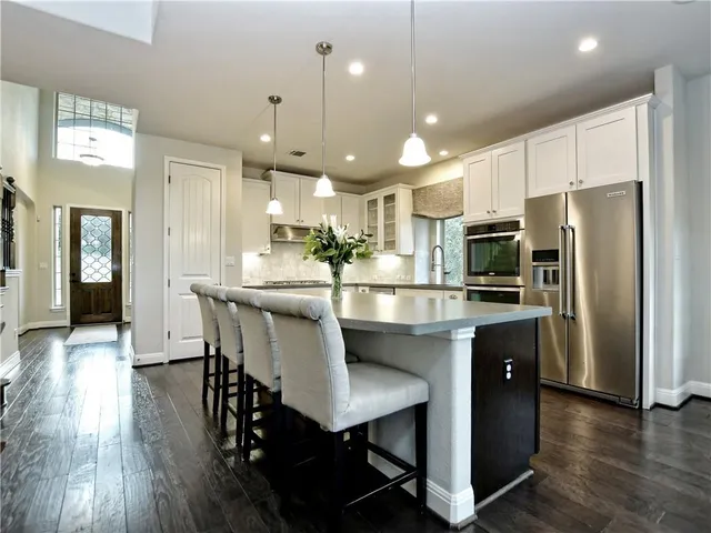 a kitchen with stainless steel appliances a dining table chairs refrigerator and microwave