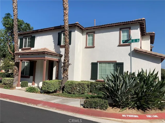 a view of a white house with large windows and a yard with plants