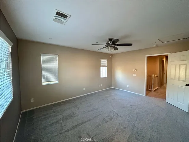 an empty room with windows and ceiling fan view