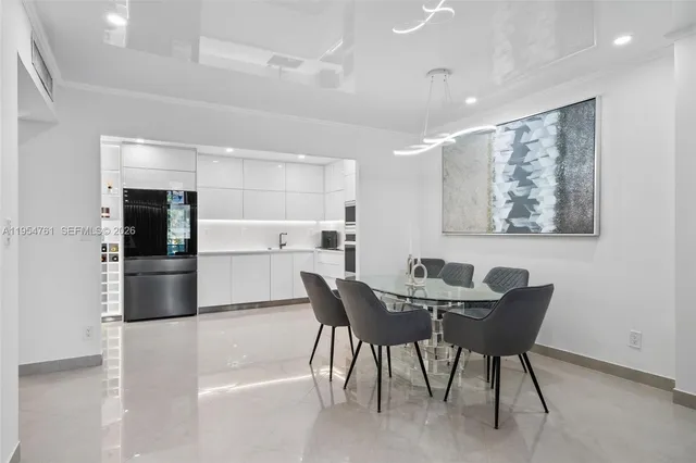 a kitchen with stainless steel appliances kitchen island granite countertop a dining table chairs and refrigerator