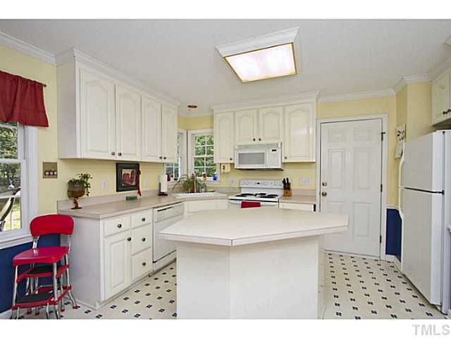 1117 Urania Drive Raleigh, NC 27603 - Photo 10 of 25 a kitchen with stainless steel appliances a stove a sink a refrigerator white cabinets and wooden cabinets