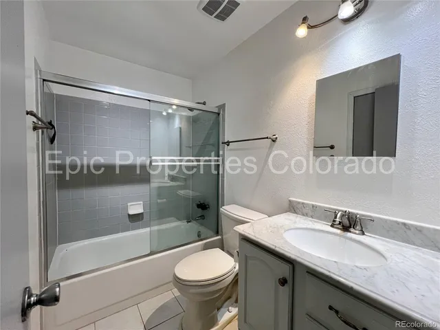 a bathroom with a granite countertop sink toilet mirror and shower
