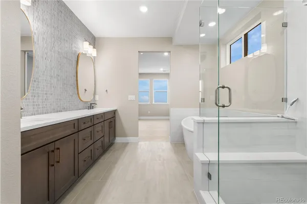 a en suite bathroom with a double vanity sink a large mirror and a bathtub