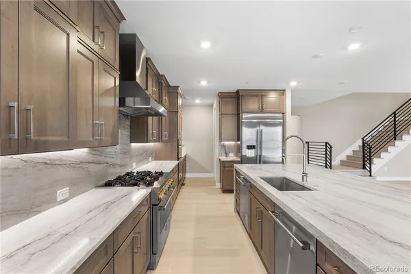 a kitchen with stainless steel appliances granite countertop a sink a stove and a wooden floors