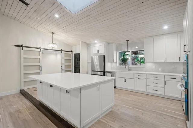 a kitchen that has a lot of white cabinets and stainless steel appliances