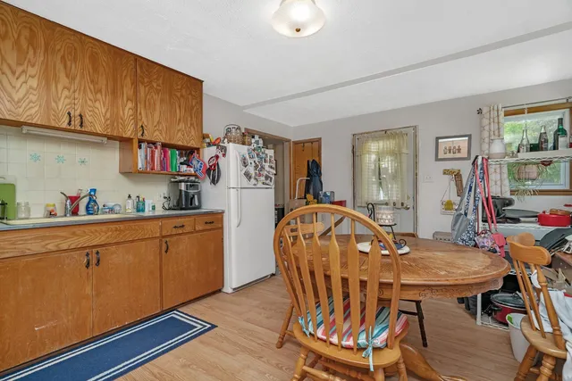 a kitchen with stainless steel appliances granite countertop a dining table chairs refrigerator and sink