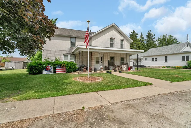 a view of a white house in front of a yard with many windows