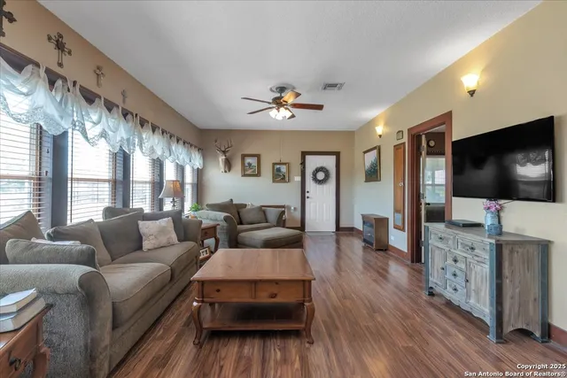 a living room with furniture large window and wooden floor