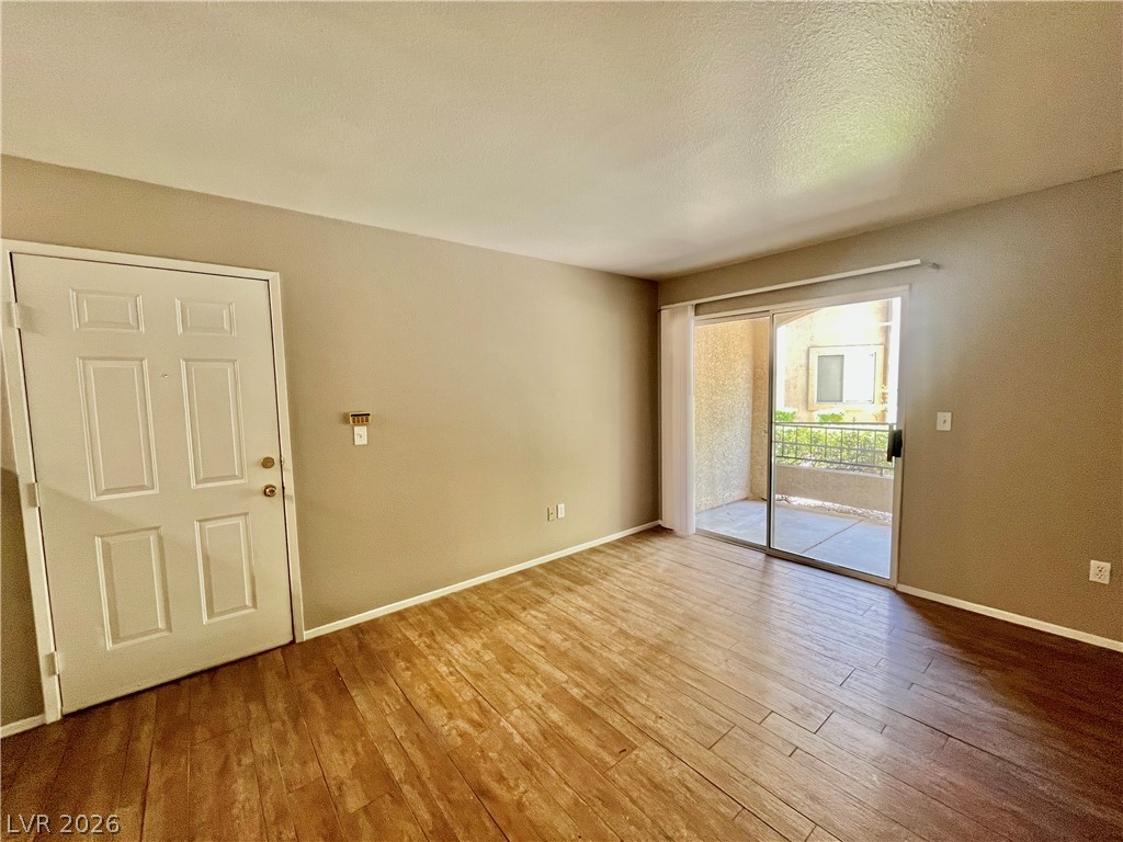 7885 West Flamingo Road, Unit 1029 Las Vegas, NV 89147 - Photo 5 of 18 Hardwood-style flooring and a sliding glass door define this airy living space.