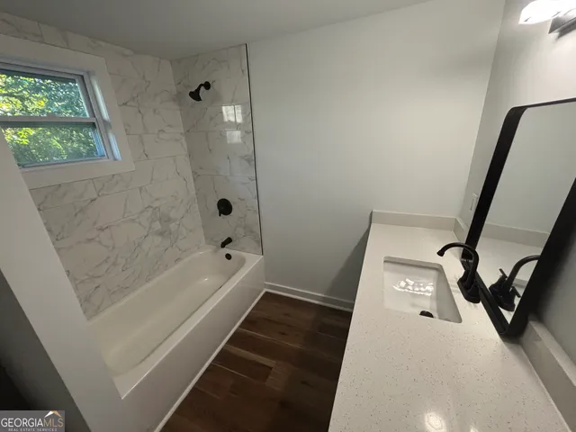 a bathroom with a tub shower vanity and a sink