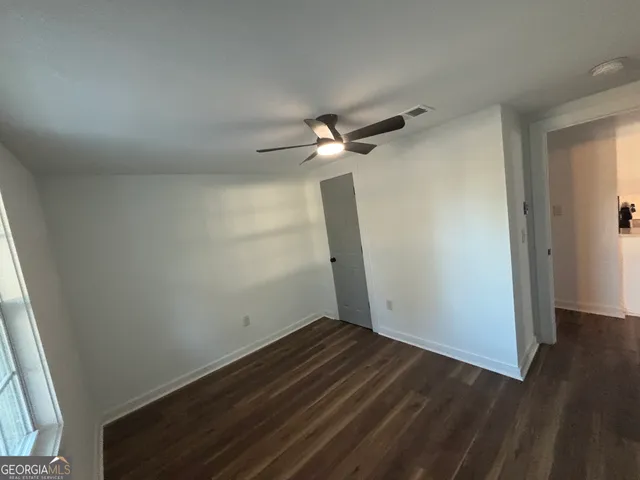 an empty room with wooden floor and fan